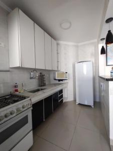 uma cozinha com armários brancos e um frigorífico branco em Pérola Home - Guarujá no Guarujá