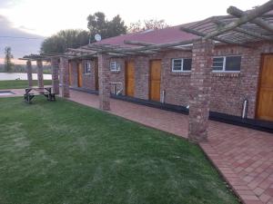 a brick house with a patio and a grass yard at Bydand B&B in Addo