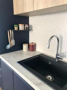 Küche mit schwarzem Waschbecken in der Unterkunft Direction Sud ! in Narbonne-Plage