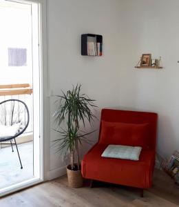 ein roter Sessel in einem Wohnzimmer mit einer Pflanze in der Unterkunft Direction Sud ! in Narbonne-Plage + 12 Fotos