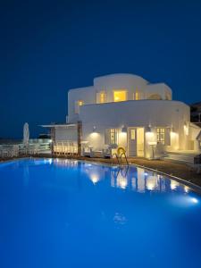 a large swimming pool in front of a building at night at Aspalathras White Hotel in Chora Folegandros