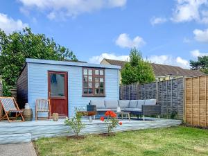 a blue shed with a couch and chairs in a yard at The Warblers in Minehead