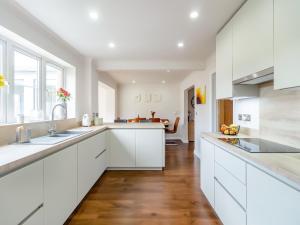 a kitchen with white cabinets and a wooden floor at Chestnut House in Bridgend