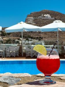 a drink sitting on a table next to a pool at Aspalathras White Hotel in Chora Folegandros