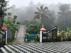 a gate on a driveway with a palm tree in the background at Arabian Nights Munnar in Munnar