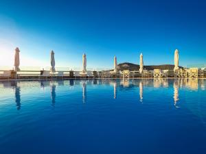 una piscina con sombrillas, mesas y sillas en Aspalathras White Hotel, en Chora Folegandros