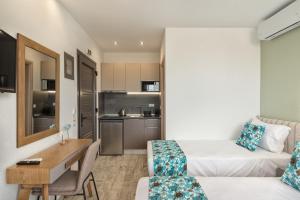a small room with a bed and a desk and a kitchen at THEA Luxury Apartments in Vourvourou