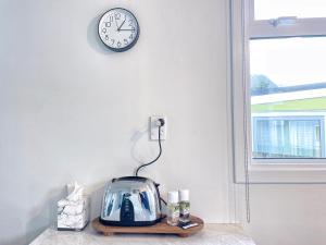 um relógio numa parede com uma torradeira numa prateleira em Cozy n Comfortable,5 mins to airport em Wellington