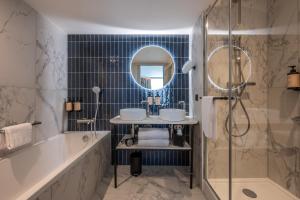 a bathroom with a tub and a sink and a mirror at Mercure La Rochelle Vieux Port in La Rochelle