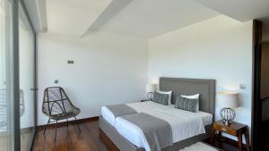 a white bedroom with a bed and a chair at Passion by Check-in Portugal in Albufeira
