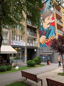 un banco frente a un edificio con un gran mural en My scandinavian home, en Sarajevo