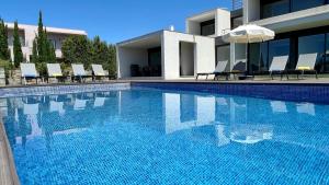 a swimming pool with chairs and an umbrella next to a house at Passion - Private Pool - 10 Guests - Albufeira in Albufeira +41 photos