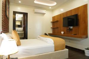 a bedroom with a bed with a flat screen tv at The Royal Hotel in Haldwāni