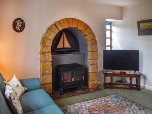 a living room with a fireplace and a tv at Peters in Tarskavaig