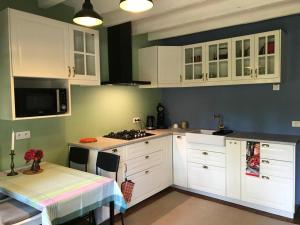 a kitchen with white cabinets and a table and a stove at The cosy retreat in Mornay-sur-Allier
