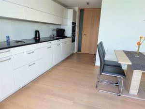 cocina con armarios blancos, mesa y sillas en Wohnung *AusZeit*, en Weiler