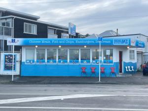 een blauw gebouw met rode stoelen ervoor bij Cozy n Comfortable,5 mins to airport in Wellington