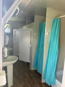 a bathroom with blue shower curtains and a sink at SUN GARDEN AND POOL 
