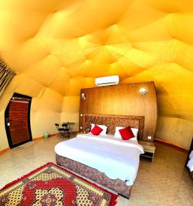 a bedroom with a large bed in a yellow wall at Darien Luxury Camp in Wadi Rum