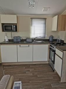 a kitchen with white cabinets and a stove top oven at The mistral golden gate towyn in Kinmel Bay