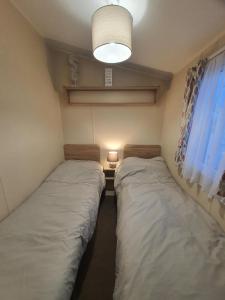 two beds in a small room with a light and a window at The mistral golden gate towyn in Kinmel Bay
