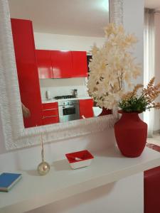 una cocina con armarios rojos y un jarrón con flores en un mostrador en Il Nido Rosso, en Foligno