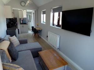 uma sala de estar com um sofá e uma televisão na parede em Annex @ 433 