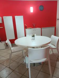 una mesa blanca y sillas en una habitación con una pared roja en Il Nido Rosso, en Foligno