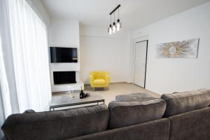 ein Wohnzimmer mit einem Sofa und einem gelben Stuhl in der Unterkunft Ennea suites- Dark suite in Flámbouras