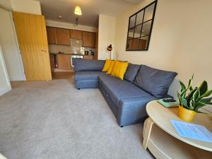 a living room with a blue couch and a kitchen at Cityscape Haven: 1 Bedroom Apartment with Terrace and City view in Bournemouth