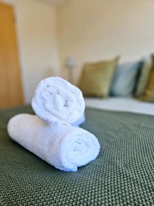 a roll of white towels sitting on a bed at Cityscape Haven: 1 Bedroom Apartment with Terrace and City view in Bournemouth