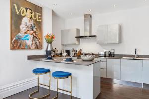 een keuken met witte kasten en blauwe krukken bij Host & Stay - Princes Park Abode in Liverpool