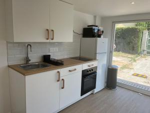 Mini maison - Oncy détend في Oncy: مطبخ بدولاب بيضاء ومغسلة وثلاجة