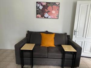 a black couch with a yellow pillow and two tables at Affordable Inn in Perth