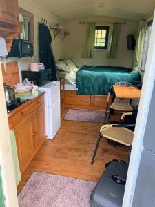 Snug & Secluded Lakeside Shepherds Hut 'Carp' في يوكفيلد: غرفة صغيرة بها سرير ومطبخ