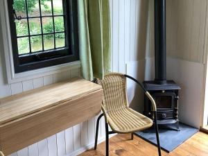 una silla sentada junto a una estufa en una habitación en Snug & Secluded Lakeside Shepherds Hut 'Carp' en Uckfield
