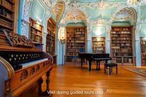 a library with a piano in a room with books at Abdij Hotel Rolduc in Kerkrade