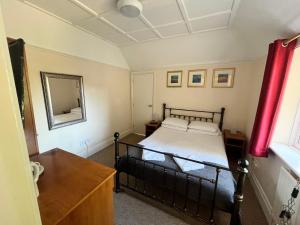 a bedroom with a black bed and a mirror at The Admirals Inn Guest House in Bracknell