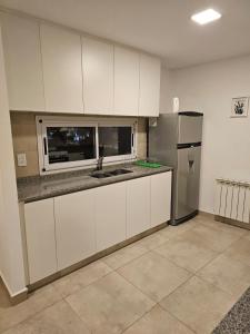 a kitchen with white cabinets and a stainless steel refrigerator at Dpto La Tacuara in Ciudad Lujan de Cuyo