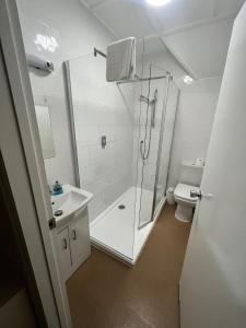 a white bathroom with a shower and a toilet at The Admirals Inn Guest House in Bracknell