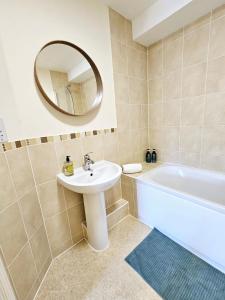 a bathroom with a sink and a tub and a mirror at Cityscape Haven: 1 Bedroom Apartment with Terrace and City view in Bournemouth