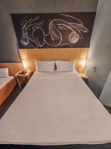 um quarto com uma grande cama branca e um quadro na parede em ibis Rio de Janeiro Centro no Rio de Janeiro