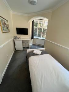 Schlafzimmer mit einem Bett, einem Schreibtisch und einem TV in der Unterkunft The Admirals Inn Guest House in Bracknell