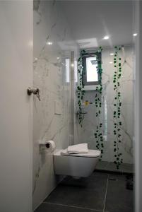 a bathroom with a toilet and a shower with green vines at Homey Comfort Apartments in Athens