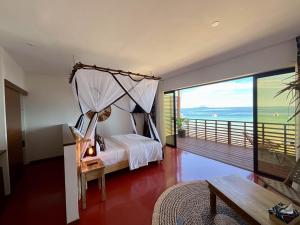 Schlafzimmer mit Himmelbett und Balkon in der Unterkunft Maison Ylang Dive Center in Nosy Be