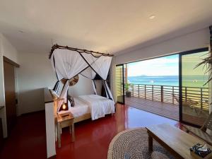 a bedroom with a canopy bed and a balcony at Maison Ylang Dive Center in Nosy Be