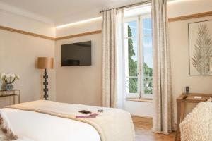 a bedroom with a bed and a large window at La Nauve, Hôtel & Jardin - Relais & Châteaux in Cognac