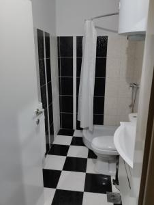Łazienka z toaletą i czarno-białą podłogą wyłożoną szachownicą w obiekcie PARISKA NOC w mieście Loznica