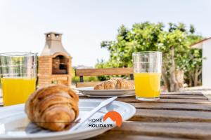 une table avec une assiette de pain et deux verres de jus d'orange dans l'établissement #178 Monte das Churras 1 by Home Holidays, à Patã de Cima