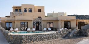 a villa with a swimming pool and a stone wall at DIPOLIS luxury apartments Syros in Episkopíon